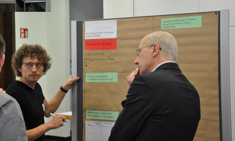 Drei Personen diskutieren vor einem Flip-Chart.