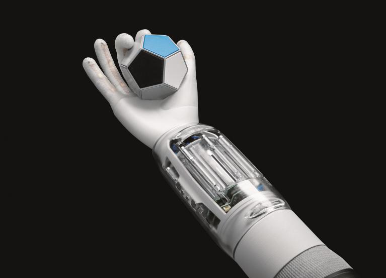 Dargestellt ist dei BionicSoftHand von Fest. Die Hand umschließt einen blauen Würfel.
