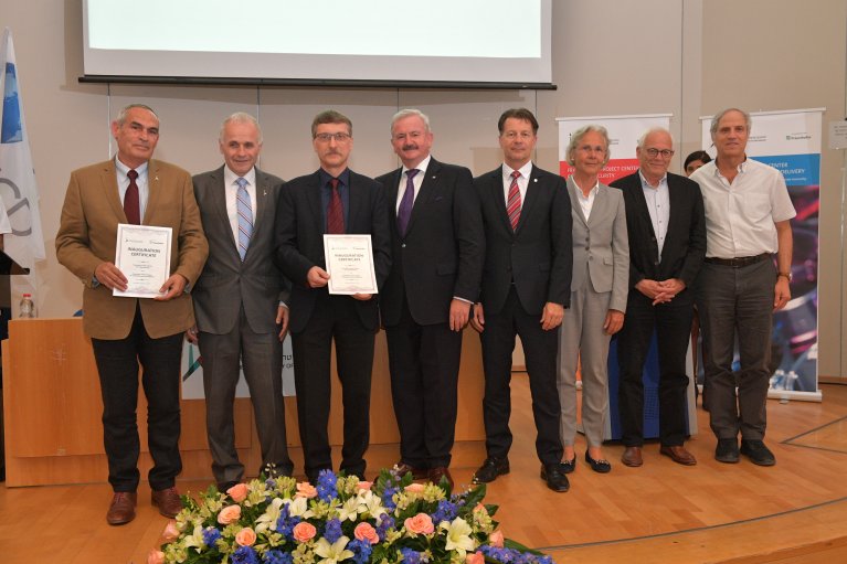 Mehrere Personen stehen für ein Guppenbild zusammen auf einer Bühne.