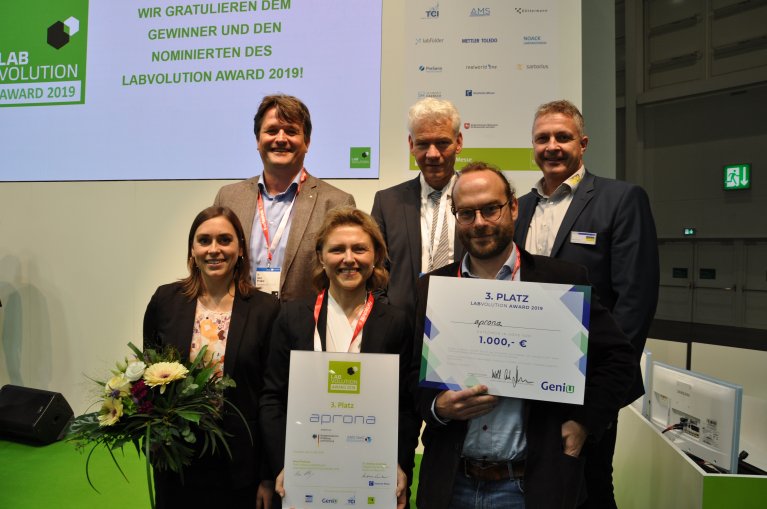 Eine Gruppe von Menschen sieht in die Kamera. Einige Personen der Gruppe halten die Urkunde über den Gewinn des Awards in den Händen.