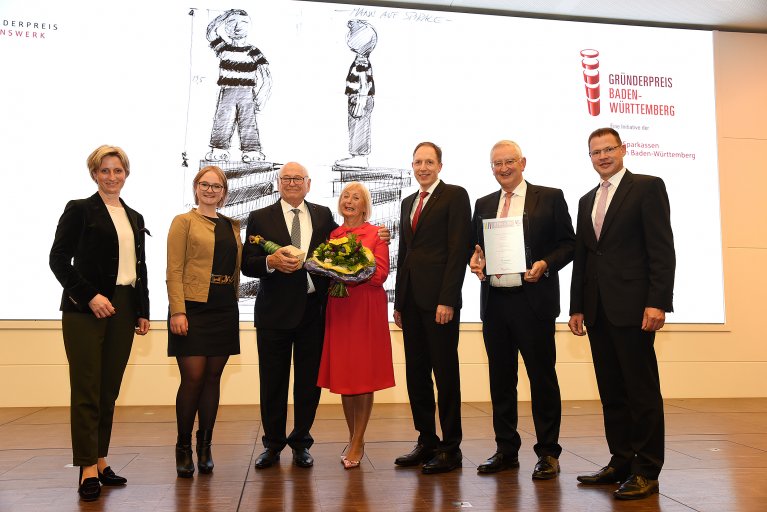 Mehrere Personen stehen für ein Guppenbild zusammen auf einer Bühne.