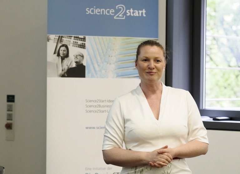 Prof. Dr. Katja Schenke-Layland steht vor einen Roll-up und begrüßt die Teilnehmer.