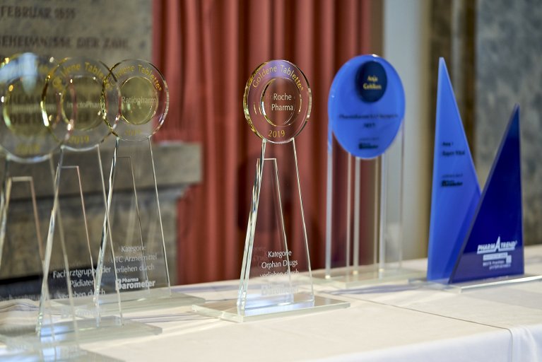 Mehrere Siegerpreise aus Glas stehen auf einem weißen Tisch.