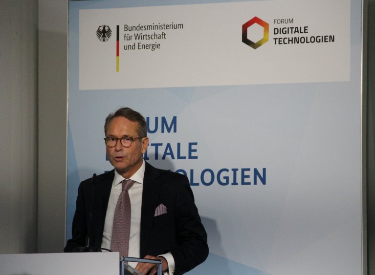 State Secretary Dr. Ulrich Nussbaum stands behind a desk and gives the opening speech