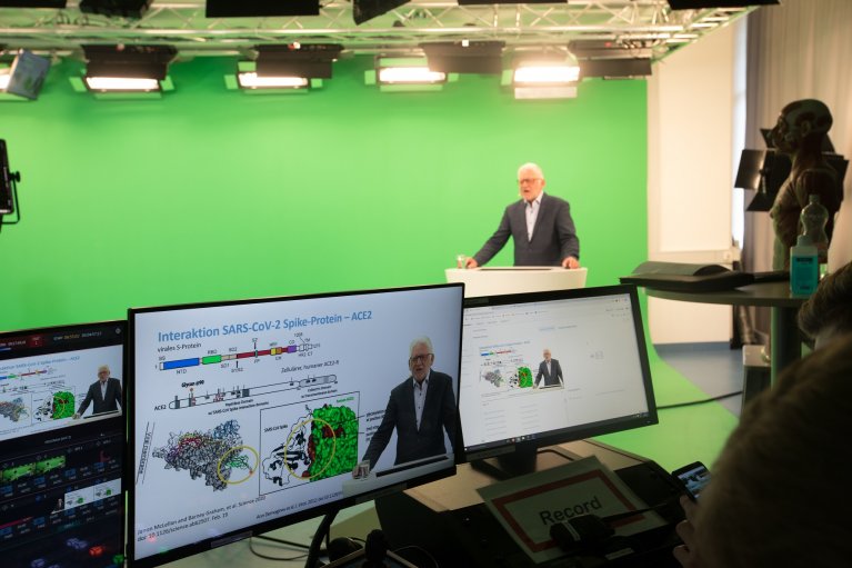 Professor Thomas Iftner steht vor einem Green-Screen während sein Vortrag aufgenommen wird.
