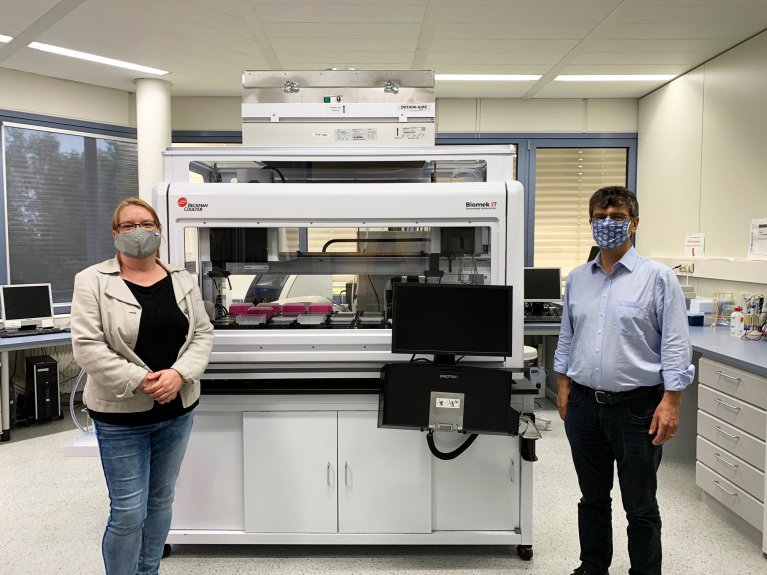 Ein Mann und eine Frau stehen vor einer Maschine in einem Labor.