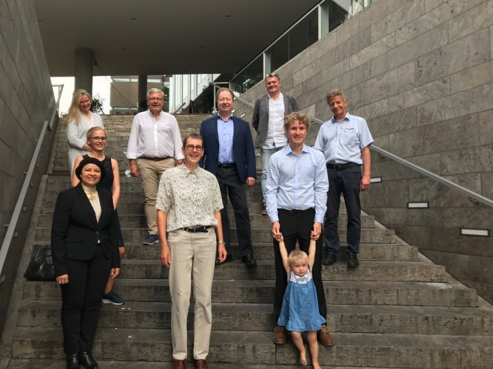 9 Personen und ein Kind stehen auf einer Treppe zum Gruppenbild