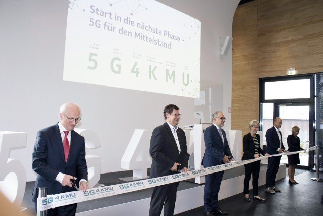 Sechs Politiker im Anzug halten jeweils eine Schere in der Hand um ein Band zu zerschneiden.