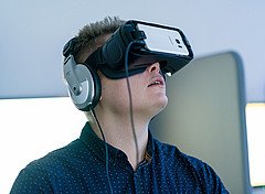Ein Mann trägt eine VR Brille und Kopfhörer.
