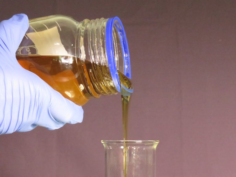 DIckflüssige Substanz wird von einem Behälter in ein Glas geschüttet