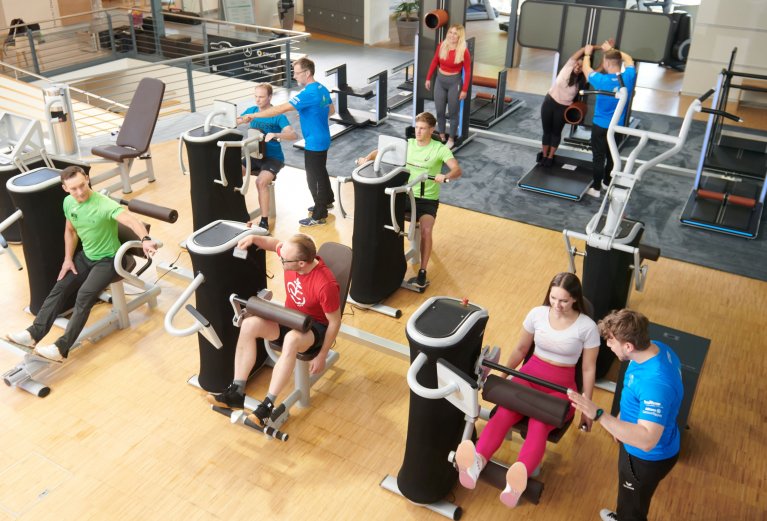 Vogel-Perspektive eines Fitnessstudium mit unterschiedlichen Geräten und Personen die diese betätigen.
