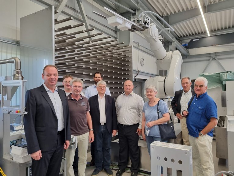 Neun Personen stehen vor einer Roboterautomatisierungsanlage .