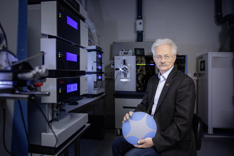 Professor Rammensee holding the BioRegio STERN Logo in his hands and stands in the lab