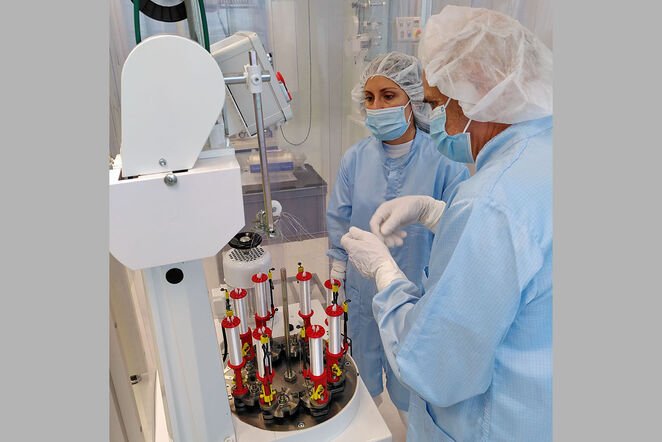 ZWeit Mitarbeiter stehen an einer Maschine für die Produktion von chirurgischen Fäden.