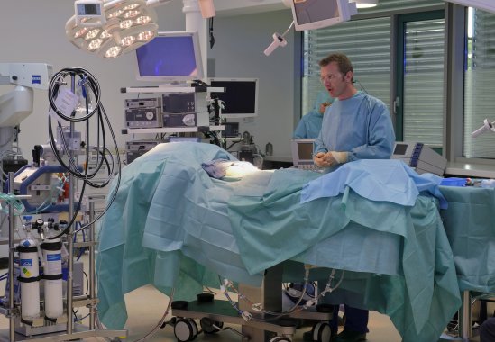 A man stands in the operating room in front of the operating table.