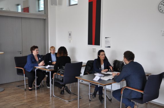Je zwei Personen sitzen sich an Tischen gegenüber und unterhalten sich.