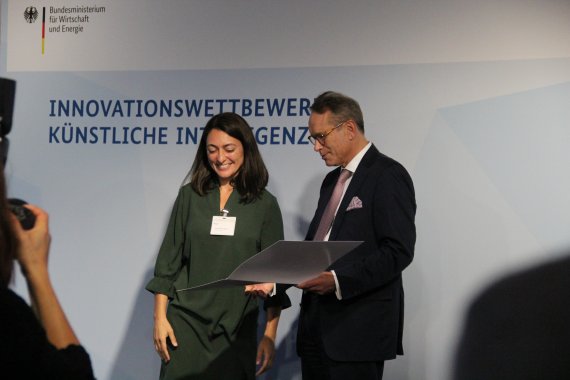 Claudia Salwiczek-Majonek steht neben Staatssekretär Dr. Ulrich Nussbaum. Dieser überreicht die Urkunde.