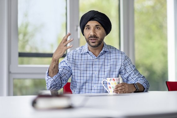Ein Foto von Herr Singh, er sitzt an einem Tisch mit einer Tasse in der Hand