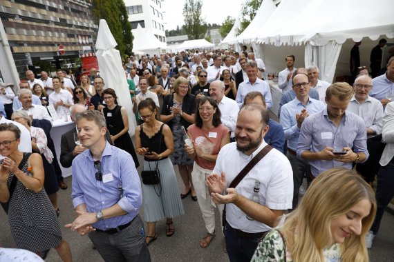 Viele Personen stehen zur Bühne gerichtet und applaudieren.